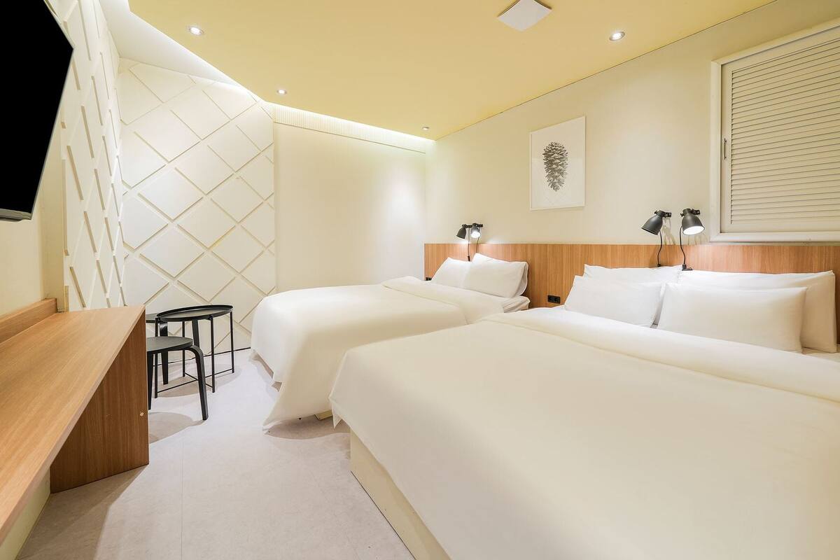 Habitación de hotel con dos camas, un escritorio y una silla.