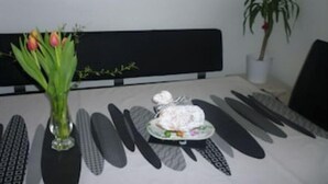 A dining table with a white tablecloth, black placemats, and a vase of tulips. - Geranium Apartment 3* (Colmar)