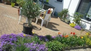 A paved patio with potted plants and a small seating area with a chair and table. - Geranium Apartment 3* (Colmar)