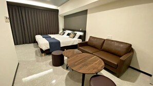 Une chambre d’hôtel moderne avec un lit, un canapé en cuir marron, une table basse en bois et une petite table ronde.