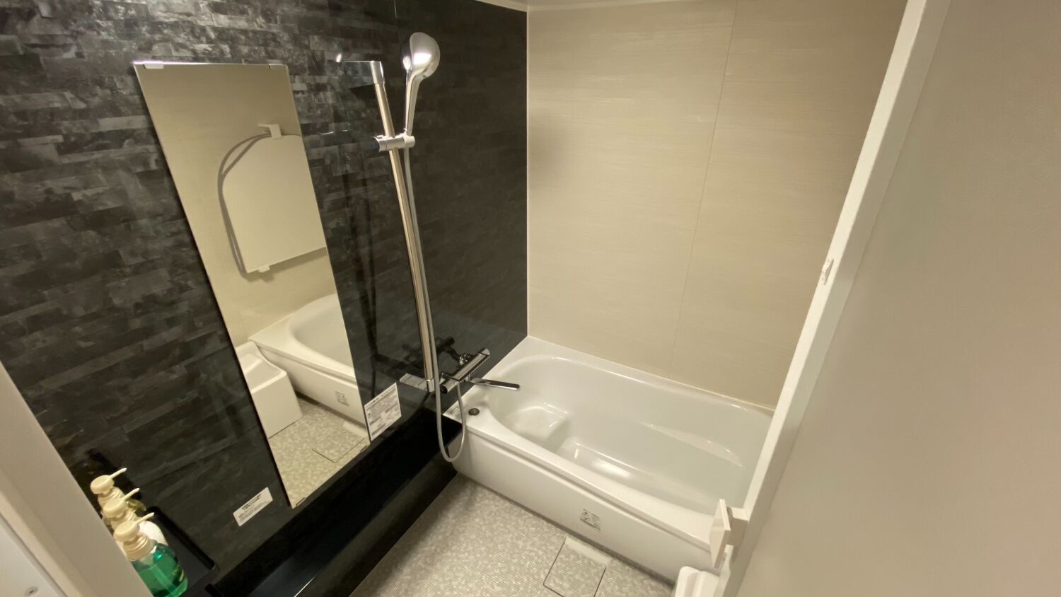 A modern bathroom with a glass shower enclosure, a white bathtub, and a large mirror.