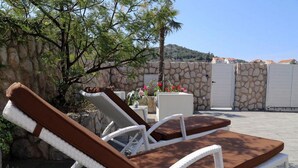 Two lounge chairs with cushions, a stone wall, and a view of a mountainous landscape. - Villa Vanda (Dubrovnik)