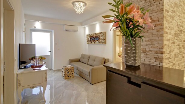 A modern living room with a beige sofa, a wooden coffee table, and a vase with flowers. - Villa Vanda (Dubrovnik)