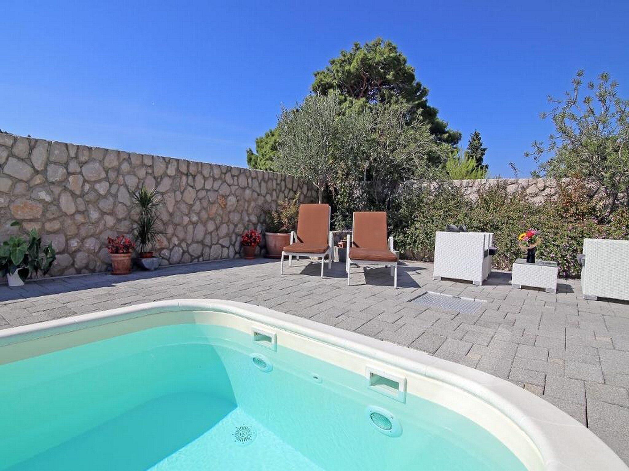 A swimming pool with lounge chairs and potted plants.