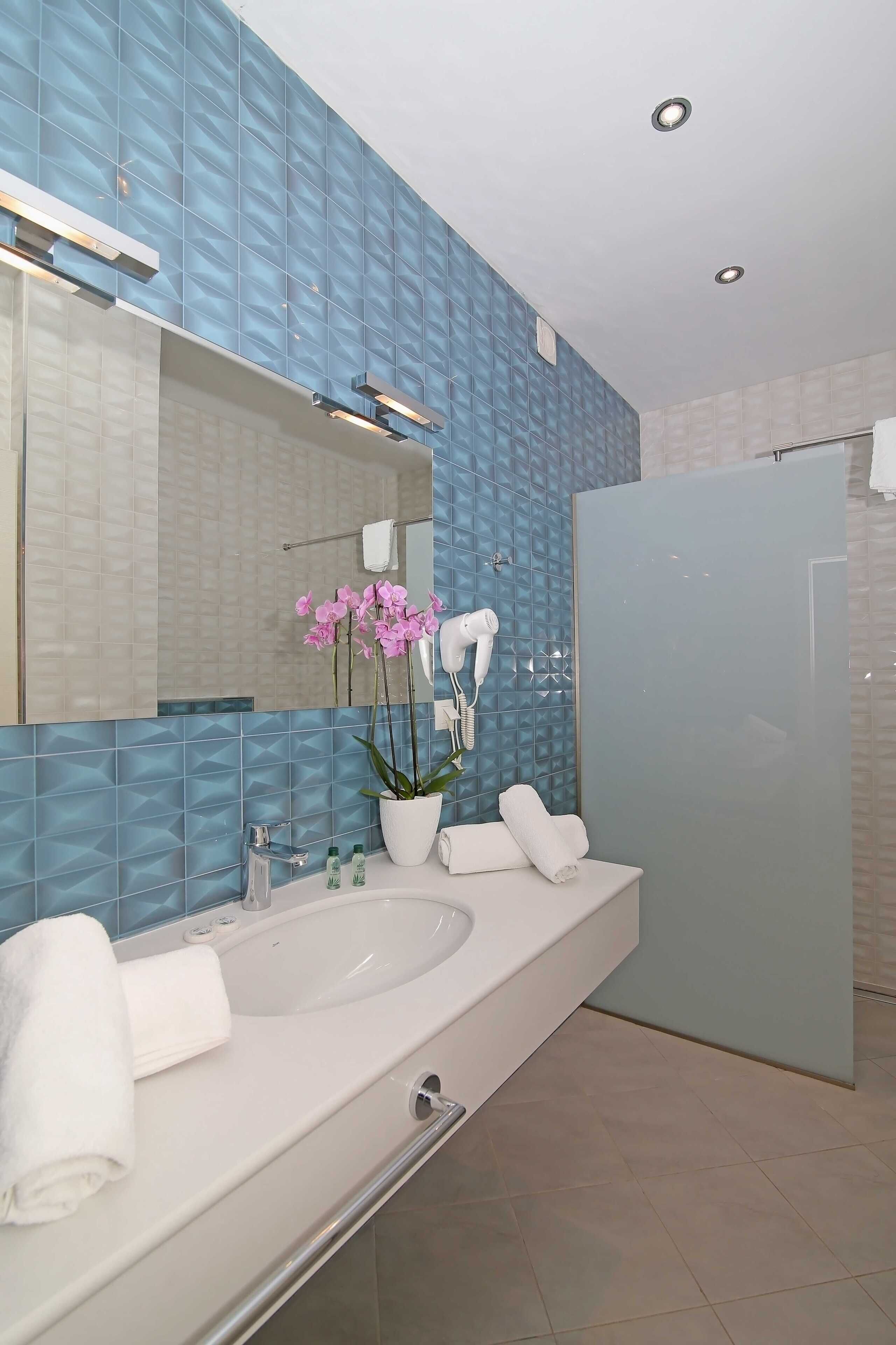 Ein modernes Badezimmer mit großem Spiegel, Waschbecken in Weiß, Badewanne und Duschbereich.