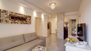 A modern living room with a beige sofa, a coffee table, a decorative wall piece, and a fruit display. - Villa Vanda (Dubrovnik)