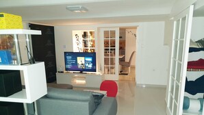A modern living room with a flat-screen TV, grey sofa, and a red chair. - Apartment Vinko, Center (Zagreb)