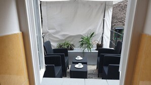A small patio area with a table and chairs, a potted plant, and a white curtain. - Apartment Vinko, Center (Zagreb)