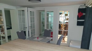 A dining area with a wooden table and chairs, a small table with a glass of water, and a view of a garden through a glass door. - Apartment Vinko, Center (Zagreb)