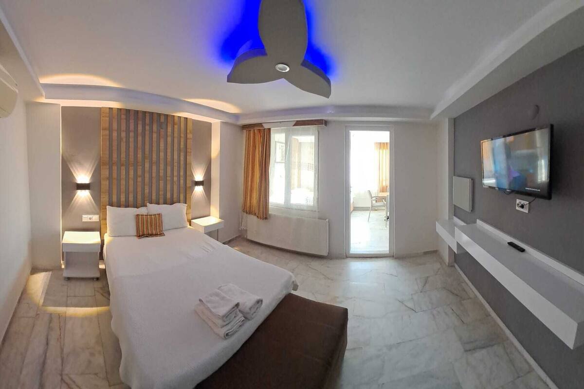A modern hotel room with a large bed, a TV, and a balcony with curtains.