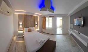 Ett modernt hotellrum med en stor säng, en TV och en balkong med gardiner.