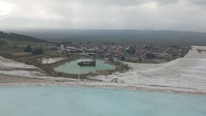 Laaja panoraamanäkymä kaupunkiin, jossa on suuri avoin alue, pieni järvi ja kaukana horisontissa kohoava vuoristo.