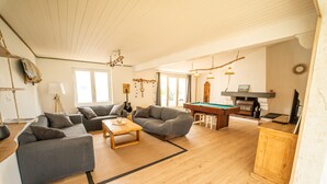 A spacious living room with a pool table, two sofas, and a wooden coffee table. - Oleron Surf House (Dolus-d'Oléron)