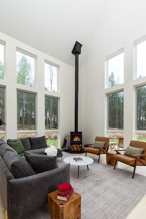 Una sala de estar moderna con chimenea, ventanas amplias y un rincón de descanso acogedor.