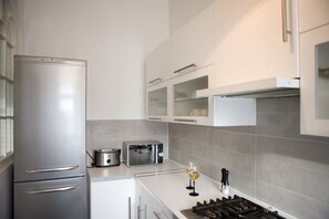 Una cocina moderna con un refrigerador de acero inoxidable, un tostador, un microondas y una estufa a gas.