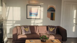 Un salon avec un canapé marron, une table basse en bois, une petite plante et un tapis en peau de vache.