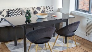 A modern dining area with a black table, two black chairs with gold legs, a wooden bowl, and patterned cushions. - Historic grade II listed Townhouse (Norwich)
