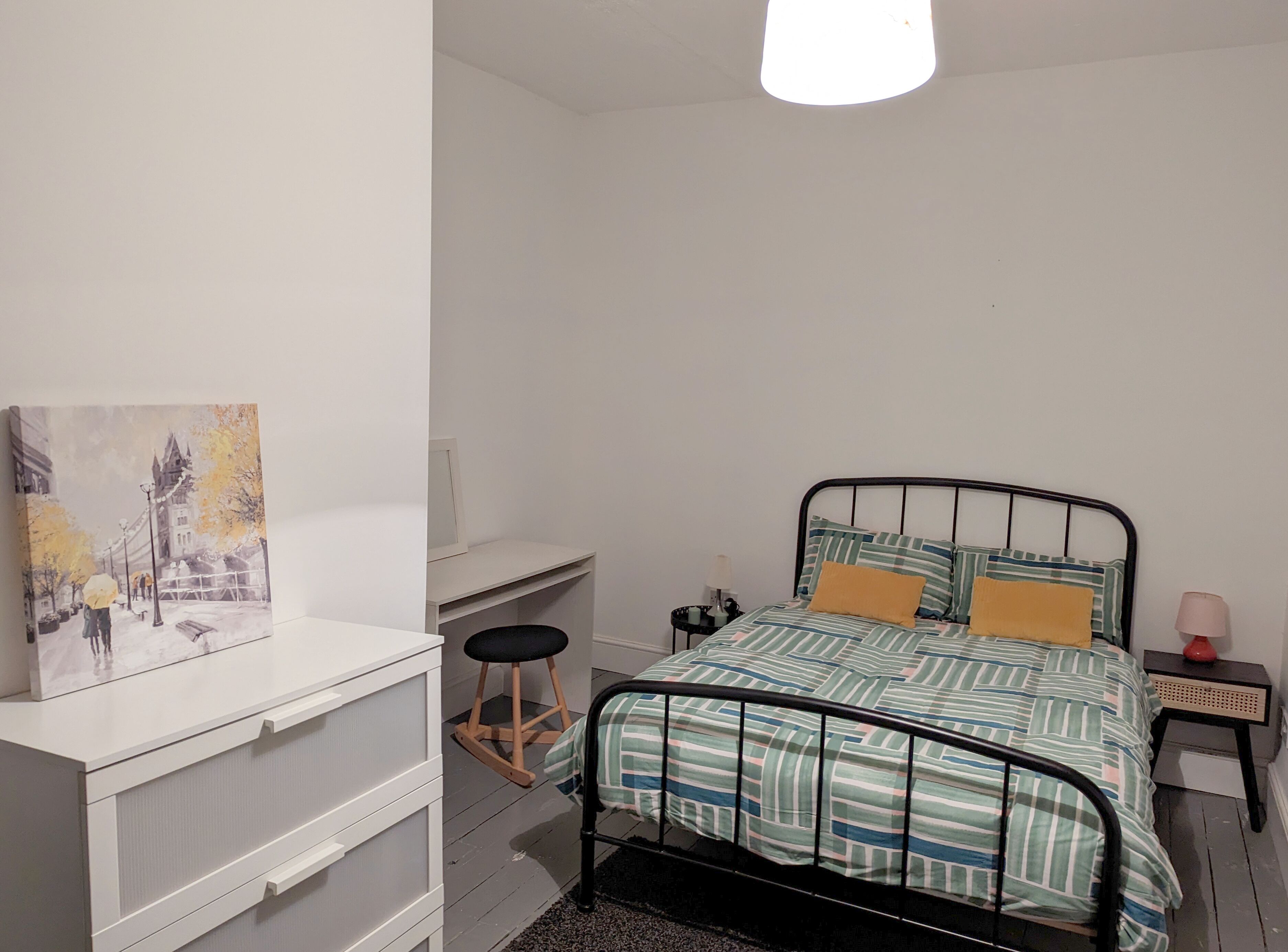 A bedroom with a bed, bedside tables, a desk, and a chair.