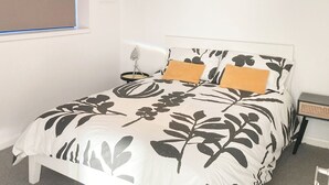 A bedroom with a bed, a bedside table, a lamp, and a window with blinds. - Historic grade II listed Townhouse (Norwich)