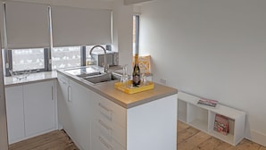 A modern kitchen with white cabinets, a wooden countertop, a built-in sink, and a window with blinds. - Historic grade II listed Townhouse (Norwich)