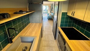 Une cuisine moderne avec des carreaux verts, des plans de travail en bois et un évier encastré.