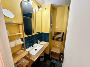 Un baño pequeño con un lavabo blanco, un espejo y un perchero para toallas.