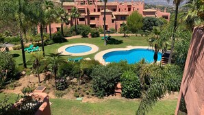 Un complejo turístico con varias piscinas, exuberante vegetación y montañas al fondo.