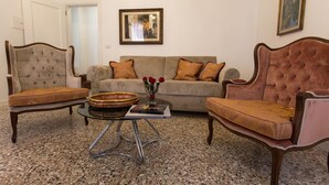A living room with a sofa, two armchairs, a coffee table, and a framed picture on the wall. - Ca' Nal Apartments, Corte Grimani Inn - BRAGOZZO (Venezia)