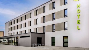 Ein modernes Bed & Breakfast Hotel mit einer sauberen Fassade, zahlreichen Fenstern und einem auffälligen, grünen Schild mit dem Namen des Hotels.