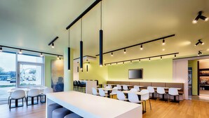 Ein moderner Konferenzraum mit langem Tisch, mehreren Stühlen und einem großen Fenster.