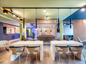 Un área de recepción moderna con mostrador, asientos y un separador decorativo.