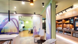 A modern interior with a dining area, seating, and a food display. - B&B Hotel Kehl (Kehl)