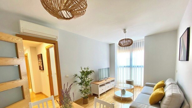 Ein modernes Wohnzimmer mit Esstisch, Sofa und Fernseher.