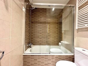 Un baño moderno con ducha de vidrio, inodoro blanco y suelo de baldosas.