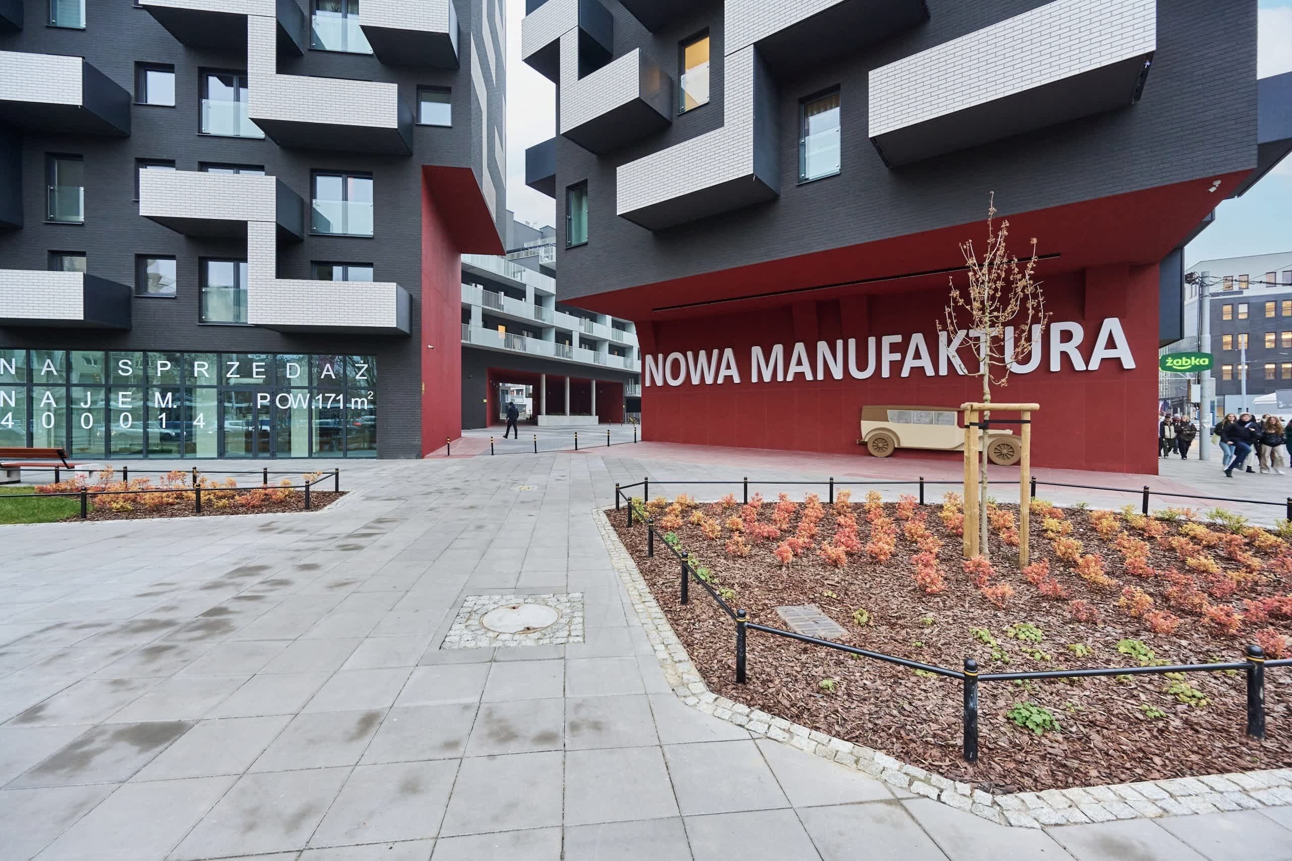 Een modern gebouw met een rode gevel en de tekst 'NOWA MANUFAKTURA'.