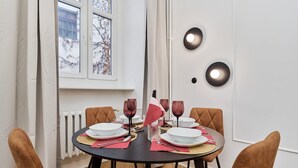 A dining area with a round table, four chairs, and a window with a view of trees. - Bright Apartment in Market Square | Pet Friendly and Place to Work (Wroclaw)