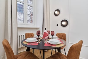 A dining area with a round table, four chairs, and a window with a view of trees.