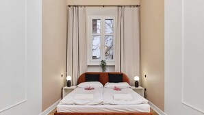 A double bed with white linens, two bedside tables with lamps, a window with curtains, and a plant on the windowsill. - Bright Apartment in Market Square | Pet Friendly and Place to Work (Wroclaw)