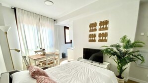 Een moderne hotelkamer met een groot bed, een bureau, een televisie en een potplant.