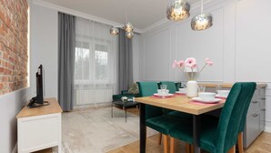 Un comedor moderno con una mesa de madera, sillas tapizadas en verde y un armario blanco.