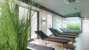 Un cuarto de spa con mesas de masaje, una planta grande en maceta y una pared con texto.