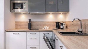 Una cocina moderna con microondas integrado, cafetera y lavavajillas.