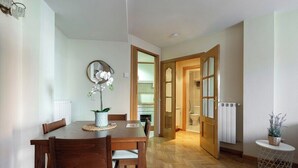 A dining area with a wooden table and chairs, a potted plant, and a mirror on the wall. - Vivodomo | Free parking, cozy, bright & central (Madrid)
