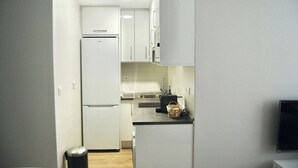 A compact kitchen with white cabinets, a built-in refrigerator, and a toaster on the countertop. - Vivodomo | New, super location, optional parking (Madrid)