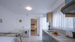 Ett kompakt kök med tvättmaskin, en matplats med bord och en liten köksdel med brödrost.
