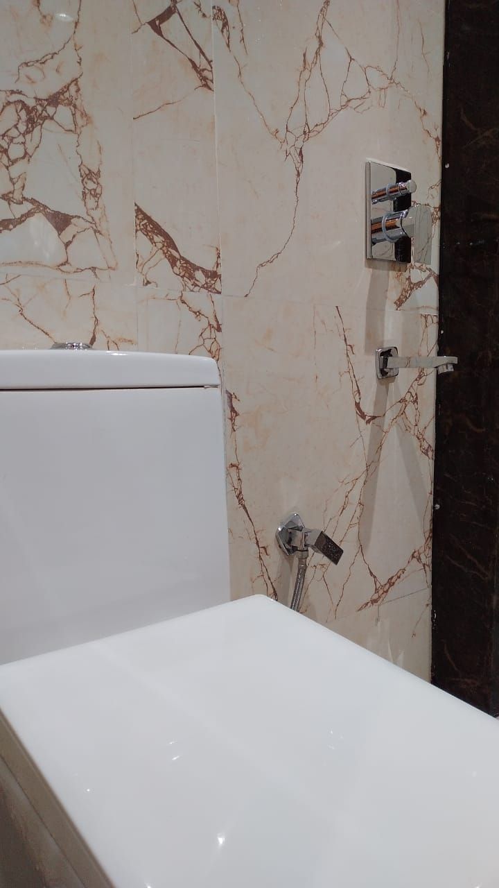 Kylpyhuone, jossa on valkoinen kylpyamme, marmoriseinä, jossa on kuvioita, ja musta työtaso.