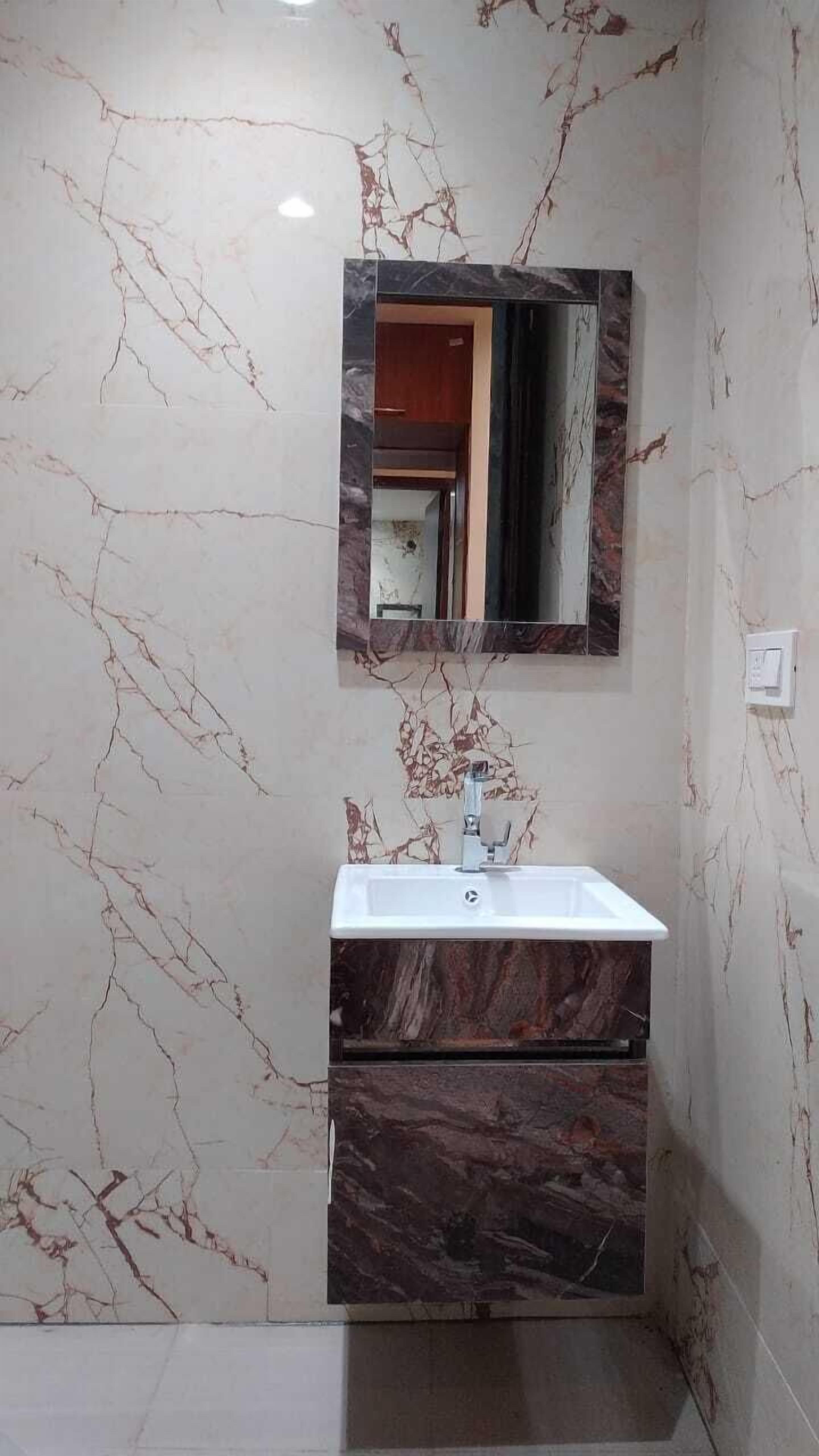 A bathroom with a marble wall, a sink, and a mirror.
