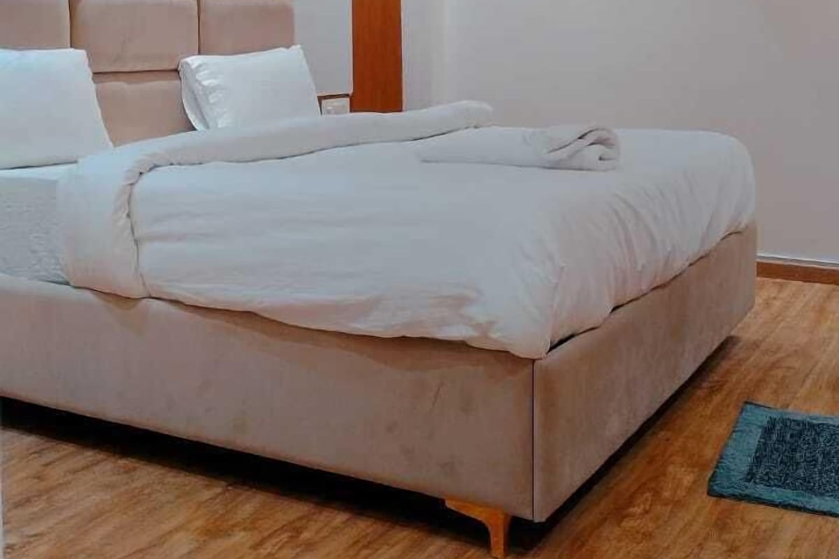 Un dormitorio con cama, cabecero de madera, ventilador de techo, equipo de aire acondicionado y suelo de madera.