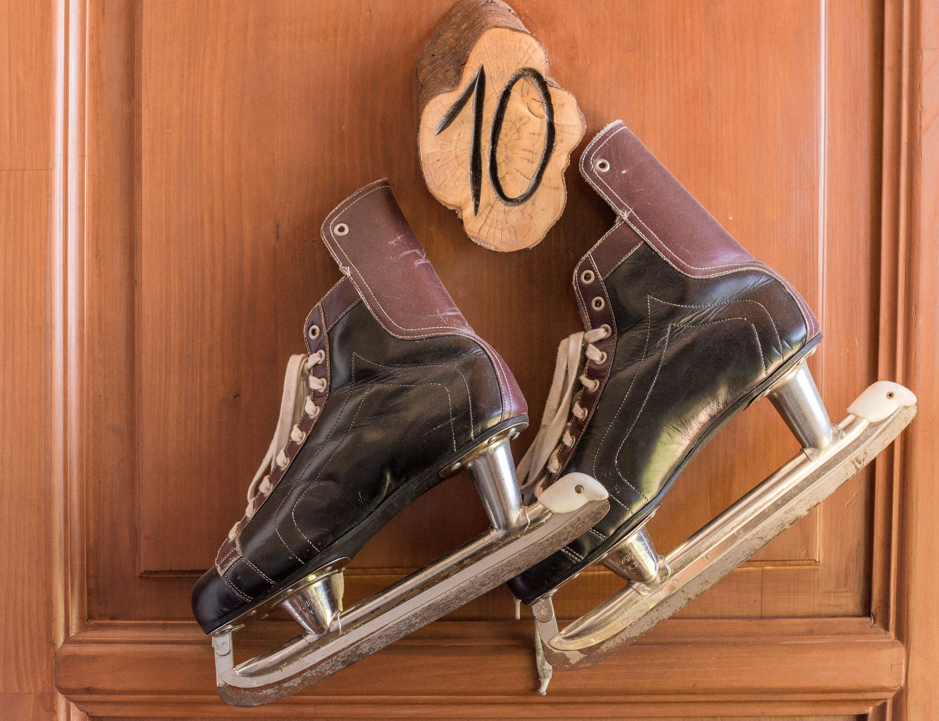 Un par de patines de hielo apoyados contra una puerta de madera con el número 10 grabado.