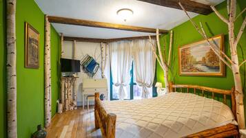 Quarto com cama de madeira, paredes verdes, televisão e janela com cortinas.
